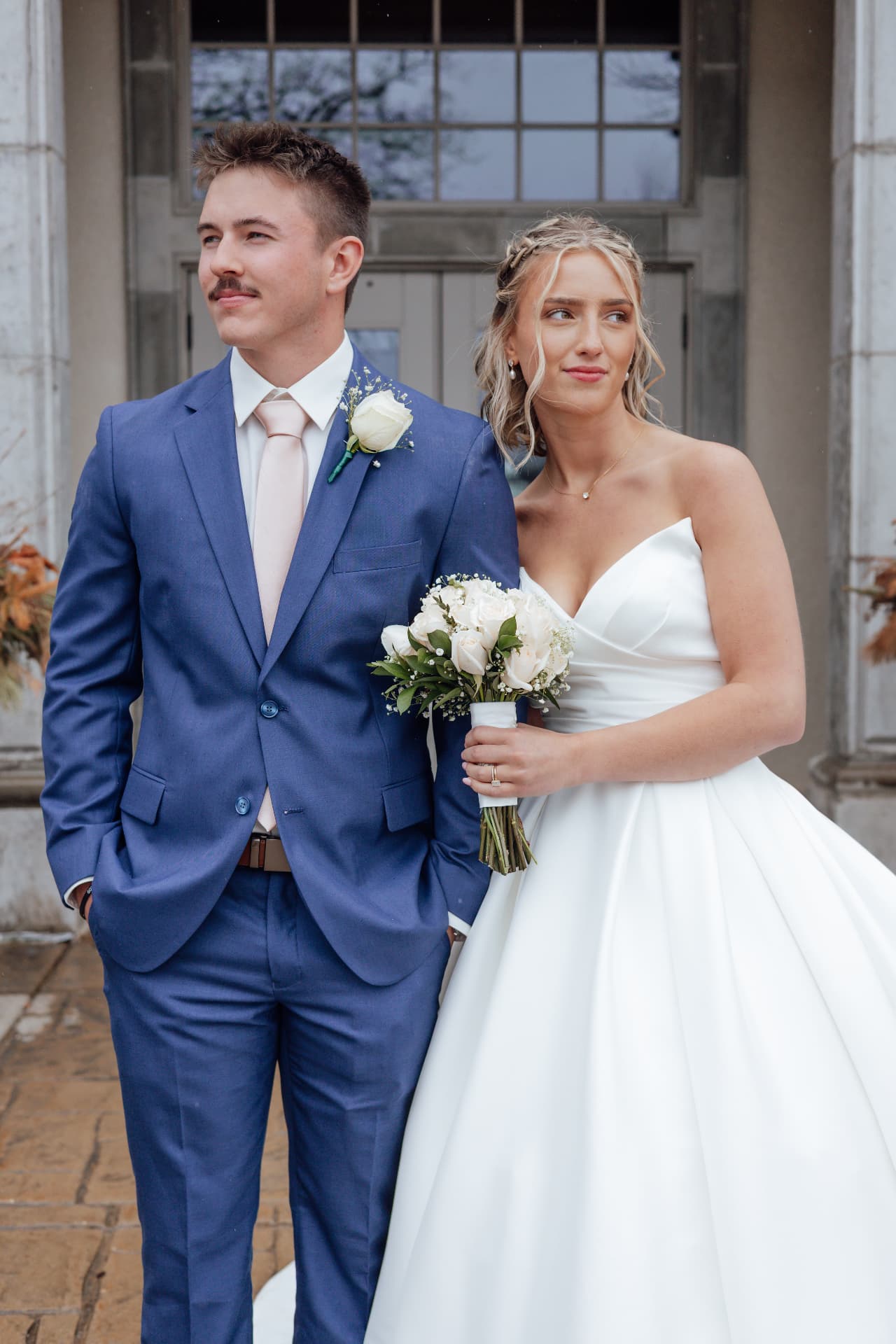 Lilly and her husband on their wedding day, holding a white rose bouquet